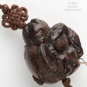Vintage hardwood carved bead depicting a boy peering into a lidded rice bowl. with cord and tassel. China 1970's. b7-wo328(e)